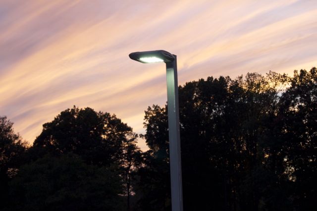 A shielded LED outdoor streetlight against a setting sky.