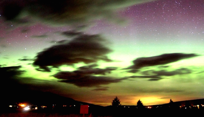 Dark clouds with the aurora borealis lighting up the sky in gree, purple and orange over Glacier National Park in Montana, U.S.