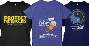 The three IDA t-shirts side by side. One says "Protect the Dark Side. Fight Light Pollution, You Must" in yellow letter; Another says Stop Light pollution and has a cat in space and the other says "Everyday needs a night" and has a ying yang.