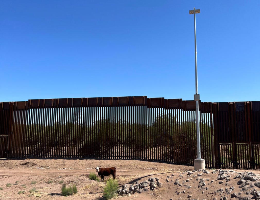 Photo of the U.S.-Mexico border wall, with a tall light next to it.