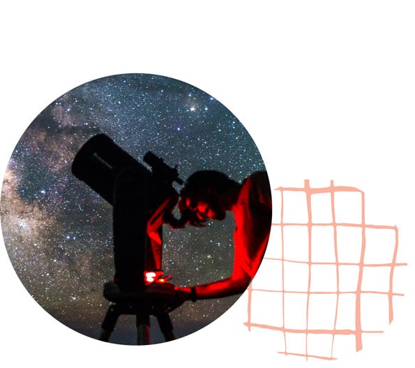 Photo of a person looking through a large telescope at the night sky.