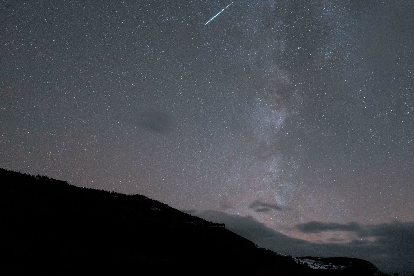 Shooting star and starry sky above a bluff in Wyoming.