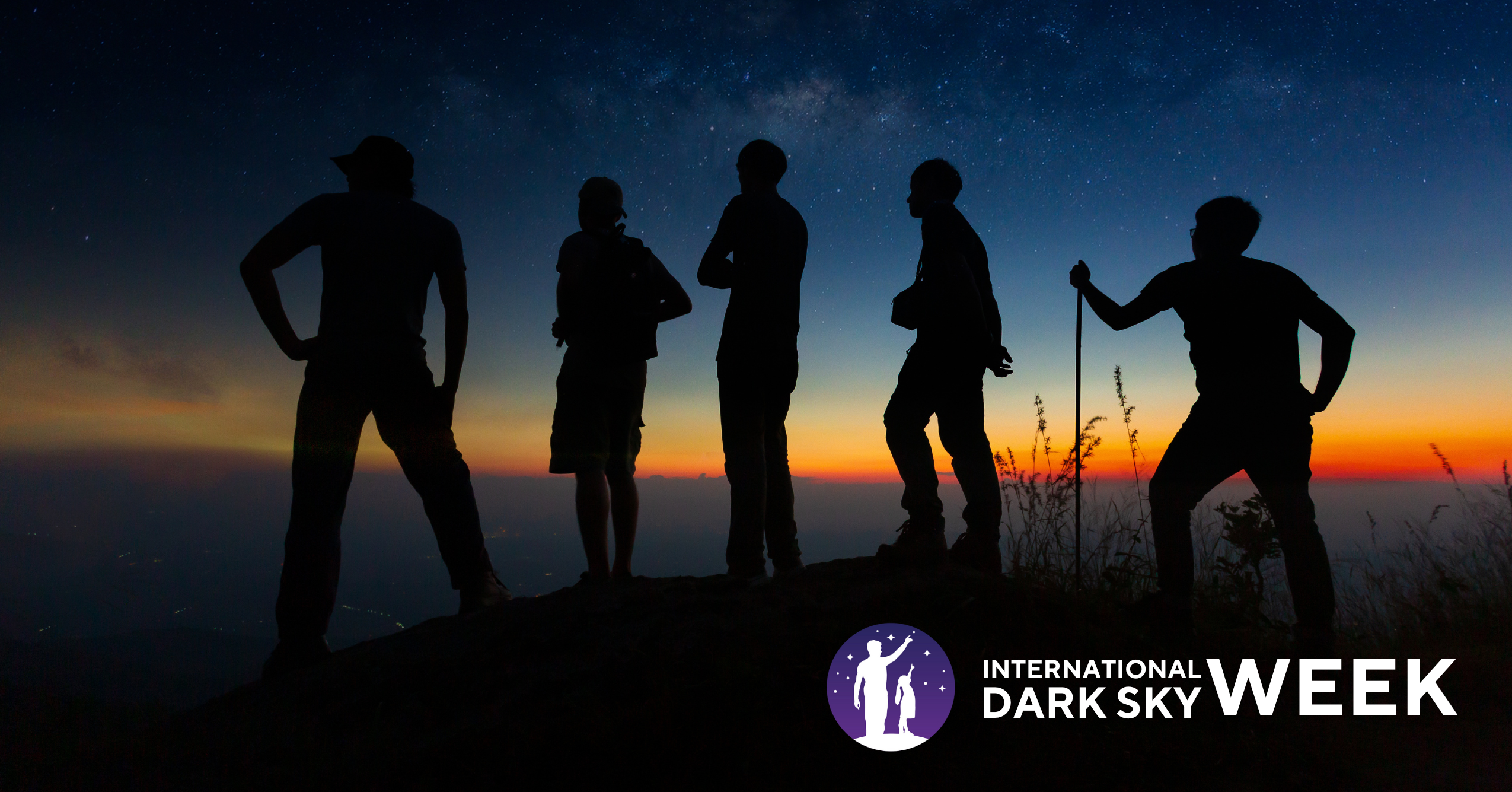 A group of hikers silhouetted by the sunset and starry sky