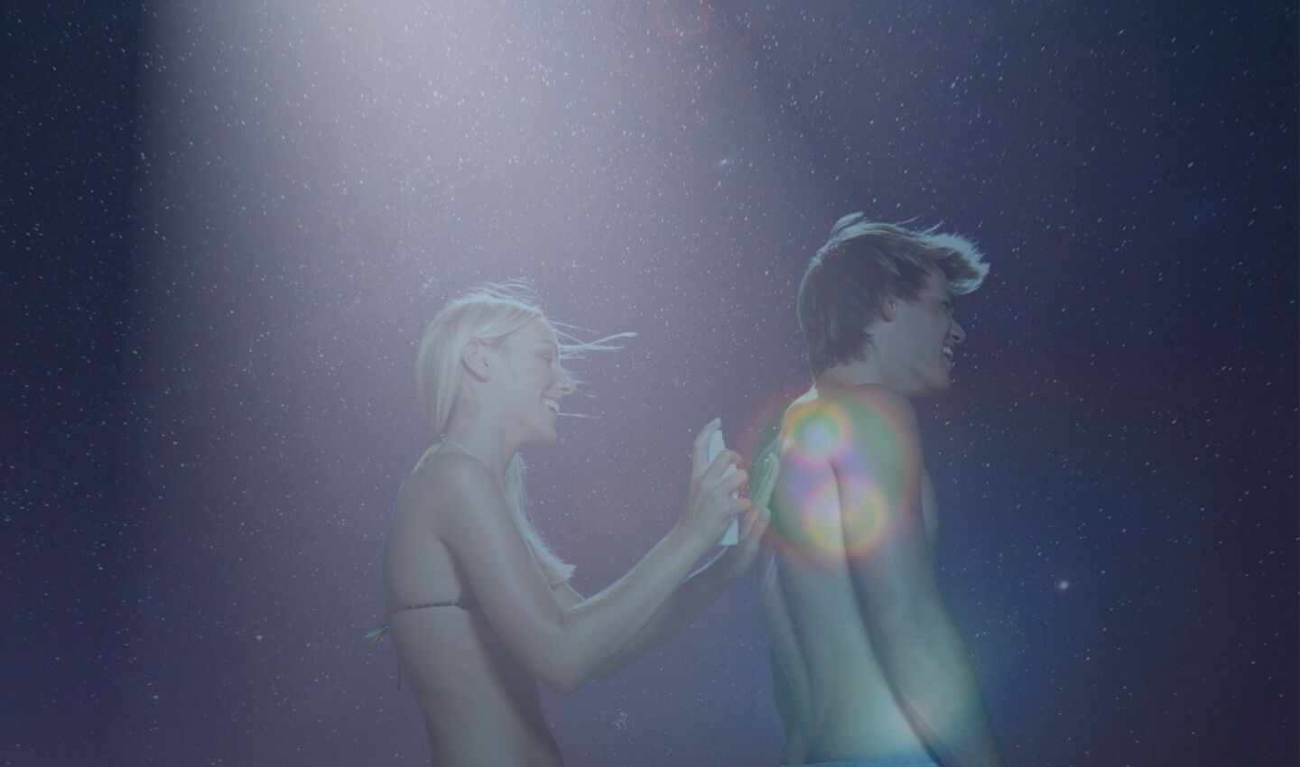 A couple applying sunscreen outside at night.