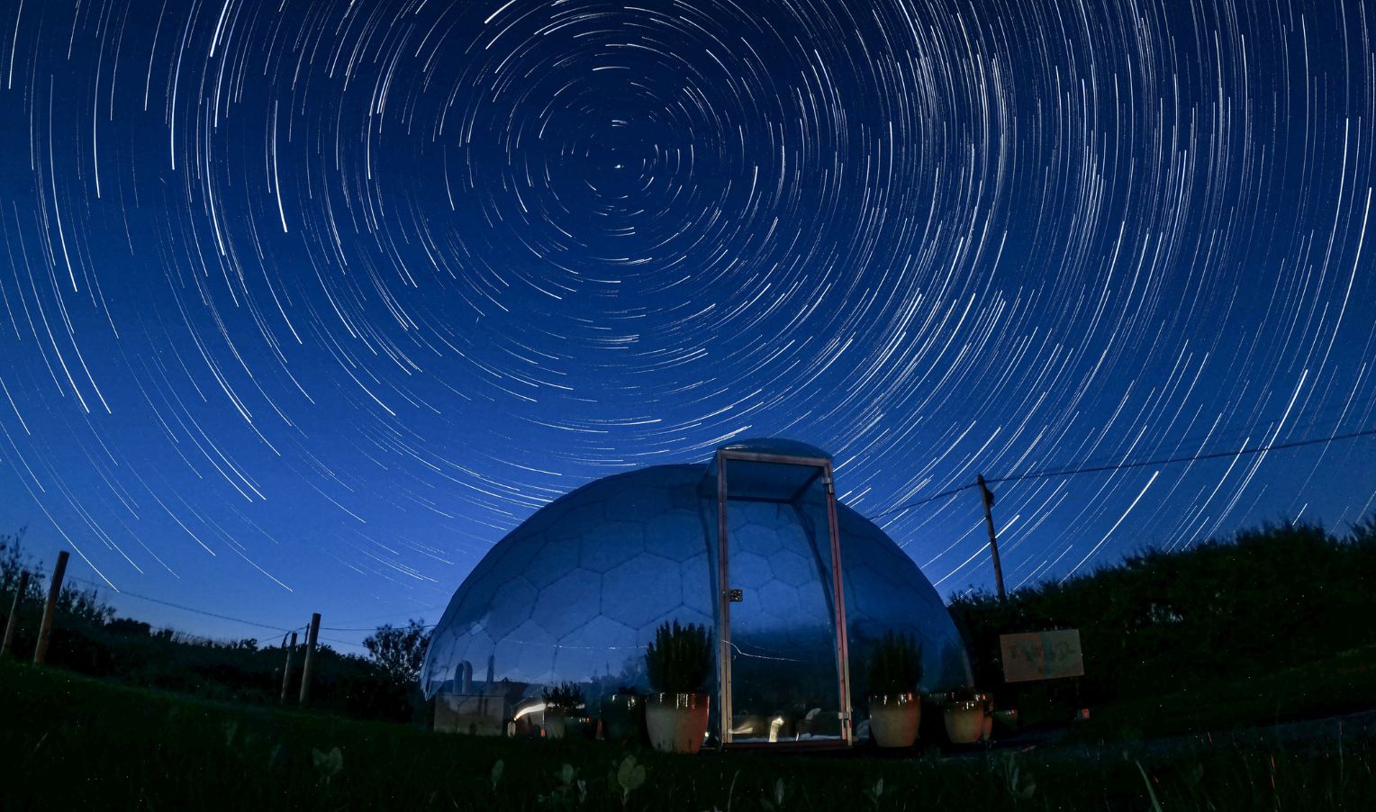 Star trails over a large glass dome at night